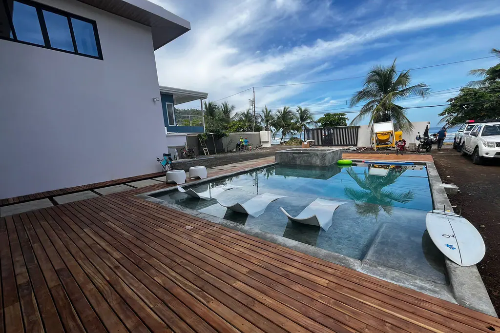 Deck de madera junto a la piscina, con la playa al fondo