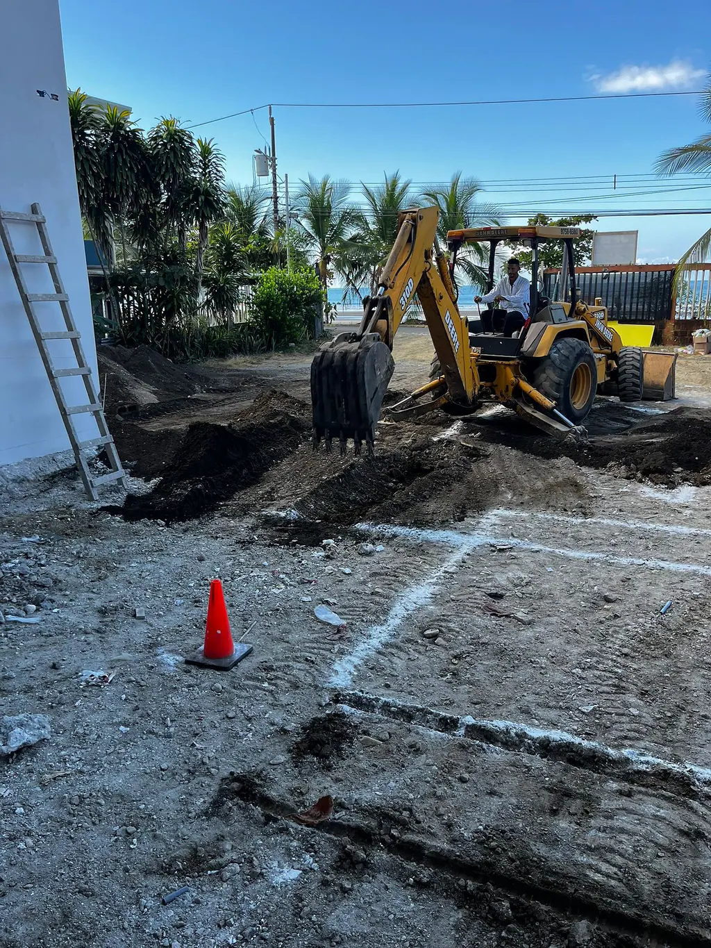 Back hoe abriendo la piscina, con el mar al fondo