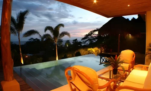 Piscina infinita iluminada con vista al mar al atardecer en Costa Rica